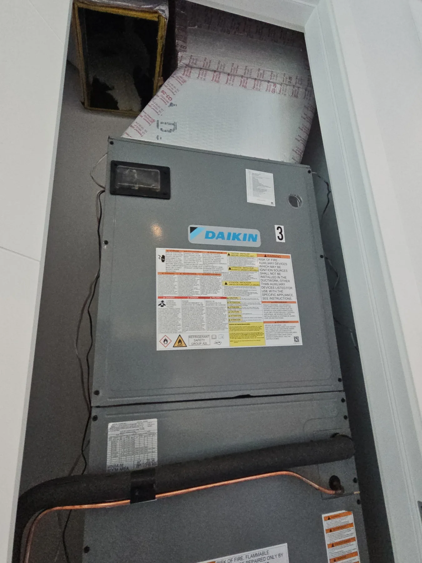 Indoor Daikin air handler installed in a utility closet with connected ductwork