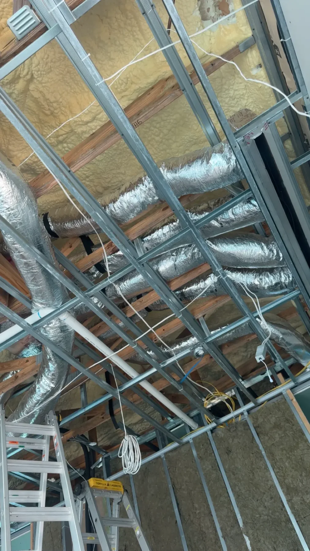 Insulated HVAC ductwork routed above metal ceiling framing