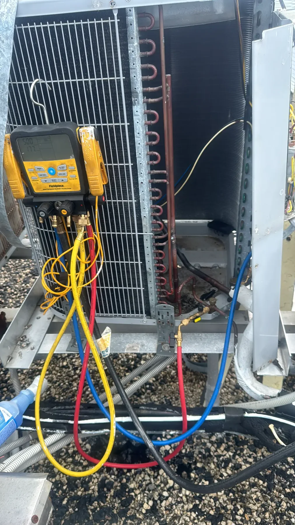 Refrigerant service gauges connected at an exposed outdoor condenser